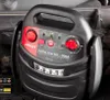 A black and red car jump starter is placed on top of a car battery. Podgląd zdjęcia produktu