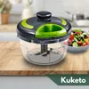 A manual food chopper is displayed on a wooden cutting board, with a salad in a bowl in the background. Produktbild-Vorschau