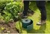 A person is using a shovel to edge a garden bed, with a roll of green garden edging in the foreground. Produktbild-Vorschau