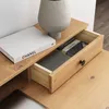 A close-up view of a wooden desk with an open drawer containing stationery and a book. Produktbild-Vorschau