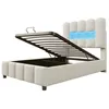 A beige upholstered bed frame with the mattress support lifted to reveal storage space underneath. The headboard has integrated blue LED lighting. Produktbild-Vorschau
