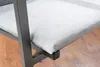 A close-up view of a light gray cushion on a dark gray metal chair frame, with a wooden floor visible in the background. Produktbild-Vorschau