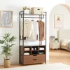 A modern wardrobe stand with clothes hanging on it, placed in a room with a bed and nightstand in the background. Produktbild-Vorschau