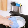 A person is washing a pot in a sink, with a dish soap dispenser and sponge holder nearby. Anteprima dell’immagine prodotto