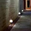 A pathway lined with solar-powered globe lights next to a concrete wall. Produktbild-Vorschau