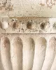 A close-up view of the textured surface of a planter, showing decorative elements and signs of wear. Produktbild-Vorschau