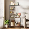 A multi-tiered shelf unit filled with decorative items and books, placed in a living room setting next to a sofa. Voir les images du produit