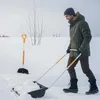 A man is shoveling snow with a snow shovel in a snowy environment. Produktbild-Vorschau