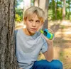 A young boy is playing in a forest with a walkie-talkie. Produktbild-Vorschau