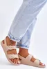 A close-up shot of a person's feet wearing beige sandals and light blue jeans. Produktbild-Vorschau