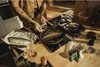 A person is cooking fish in a pan on a stovetop. Podgląd zdjęcia produktu