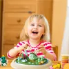 A young girl is happily playing with modeling clay, creating a dinosaur scene. Náhled obrázku produktu