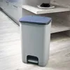 A gray pedal trash can with a blue lid sits on a light gray wood-look floor in a modern kitchen setting. Náhled obrázku produktu