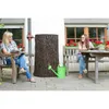 Two women are sitting in a garden setting, one reading a magazine and the other looking at a tablet, next to a tree trunk-shaped rain barrel and a watering can. Produktbild-Vorschau
