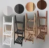 Four wooden plant stands in different colors are displayed against a light gray background. Circular swatches showing the wood grain and color of each stand are placed above them. Produktbild-Vorschau