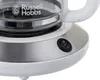Close-up of a white coffee maker base with a stainless steel accent and a power switch. Náhľad obrázku produktu