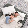 A couple sleeping on an air mattress on a patterned rug. Náhled obrázku produktu