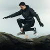 A man is balancing on a wooden balance board placed on a rock. Produktbild-Vorschau