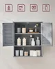 A gray bathroom cabinet with louvered doors is shown, filled with various toiletries and bathroom essentials. Produktbild-Vorschau