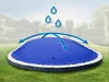 A blue pool cover on a trampoline in a garden setting, with water droplets and arrows indicating water runoff. Produktbild-Vorschau
