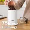 A person is pouring coffee beans into a white Bosch coffee grinder. The grinder is on a wooden surface. Text overlays indicate the maximum fill quantity. Anteprima dell’immagine prodotto