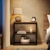 A bedside table with a lamp, books, and a candle. Anteprima dell’immagine prodotto