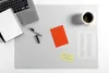 A desk setup with a laptop, notebook, pen, coffee cup, and sticky notes on a transparent desk mat. Produktbild-Vorschau