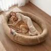 A woman and her dog are sleeping together on a large oval dog bed. Produktbild-Vorschau