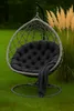 A hanging egg chair with a black cushion and a dark gray blanket draped over it, set on a green lawn with tall, tan ornamental grasses in the background. Anteprima dell’immagine prodotto