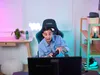 A young person is playing a video game in a room with colorful lighting. Náhled obrázku produktu