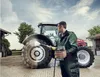 A man is pressure washing a tractor tire on a farm. Voir les images du produit