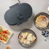 A waffle maker with waffles and berries on a countertop. Produktbild-Vorschau