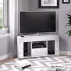 A modern white high-gloss TV stand with a television on top, placed in a living room setting with a patterned rug and a window with sheer curtains. Náhled obrázku produktu