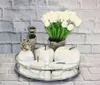 A decorative arrangement of white ceramic apples, a pineapple, a vase, and white tulips in a pot, displayed on a mirrored tray against a brick-patterned wall. Anteprima dell’immagine prodotto