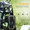 A portable radio is attached to a camouflage backpack, with outdoor scenery in the background. Podgląd zdjęcia produktu