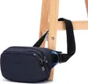 A navy blue Pacsafe hip pack is shown hanging from a wooden stool. Produktbild-Vorschau