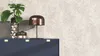 A dark blue cabinet with a decorative vase containing a monstera plant, a small cactus, and a copper lamp on top, set against a beige botanical-patterned wallpaper. Produktbild-Vorschau