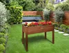 A raised wooden planter filled with colorful flowers sits on a green lawn in a garden setting. The garden features a vertical green wall, a wooden fence, and a built-in bench. Produktbild-Vorschau