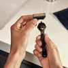 A person is holding a razor and a replacement blade, preparing to attach the blade to the razor. Anteprima dell’immagine prodotto
