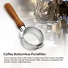A coffee bottomless portafilter with a wooden handle is shown in front of a coffee machine. Náhled obrázku produktu