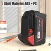 A power tool battery sits on a wooden surface with tools and a container in the background. Náhled obrázku produktu
