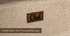 A close-up of a textured beige fabric with a brown leather label that says "Olaf". Below the label, a dark brown rectangular overlay contains the German text "Möglichkeit der Personalisierung". Produktbild-Vorschau
