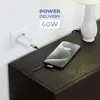 A white USB-C charger plugged into a wall socket, connected by a black and white patterned cable to a smartphone that is charging on a dark wooden nightstand next to a white lamp. Produktbild-Vorschau