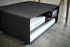 A black metal storage unit with shelves, containing white boxes and some smaller items on the top shelf. Produktbild-Vorschau