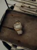 A vintage Casio digital watch with a gold-tone case and a white textile strap rests on a weathered metal surface. Voir les images du produit