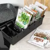 A black kitchen organizer filled with spice packets is placed on a countertop next to a stovetop. Anteprima dell’immagine prodotto