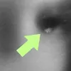 A close-up view of a metallic surface with a bright green arrow pointing to a small, textured area. Produktbild-Vorschau