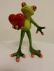 A ceramic figurine of a frog holding a red heart. Produktbild-Vorschau