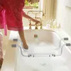 A person is filling a bathtub with water, and a bath seat is placed in the tub. Voir les images du produit