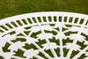 Close-up of a white ornate table top with a green grassy background. Produktbild-Vorschau
